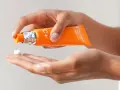 Mani che dosano crema viso con vitamina C, per illuminare e proteggere la pelle.