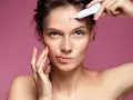 Donna applica crema su un brufolo sulla fronte, preoccupata di quanto dura un brufolo.