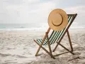 Spiaggia deserta con sdraio e cappello di paglia. Ricorda i rimedi per il colpo di calore: idratarsi e cercare l'ombra.