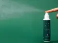 Dito come si usa il tonico viso: una mano spruzza il tonico idratante YABE su sfondo verde.