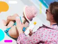 Mamma applica la crema solare alla figlia sulla spiaggia. Ricorda, prendere il sole fa bene, ma con protezione!