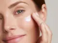 Donna applica crema contorno occhi, contrastando l'invecchiamento precoce a 60 anni. Pelle luminosa e idratata.