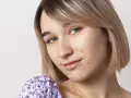 Primo piano di una giovane donna con pelle chiara e capelli biondi, che mostra segni di acne da sudore sul viso.