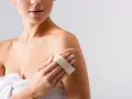 Donna usa una spazzola per il corpo per esfoliare la pelle, un segreto per come mantenere abbronzatura a lungo.