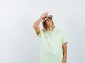 Donna con cappellino e maglietta chiara, mano sulla fronte, con espressione di chi soffre per l'insolazione quanto dura.