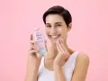 Donna sorridente con acqua micellare Lycia e dischetto di cotone, perfetta per imparare come pulire il viso quotidianamente.