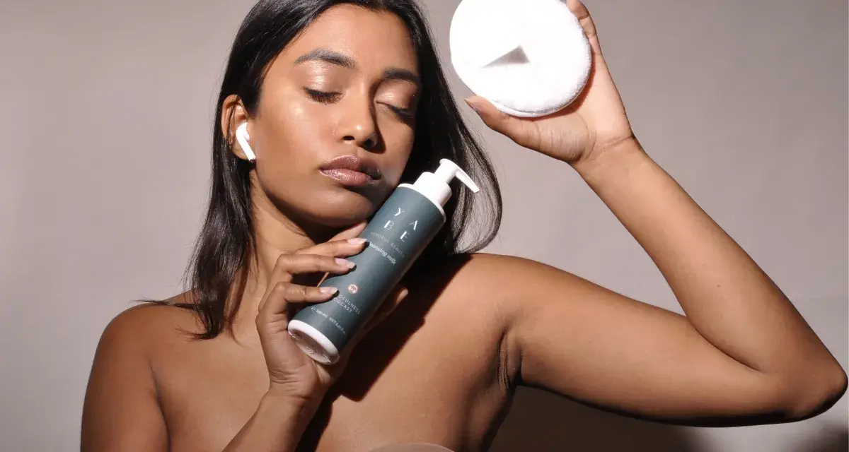 Donna con latte detergente e dischetto struccante, pronta per la pulizia del viso dopo il latte detergente il viso va lavato.