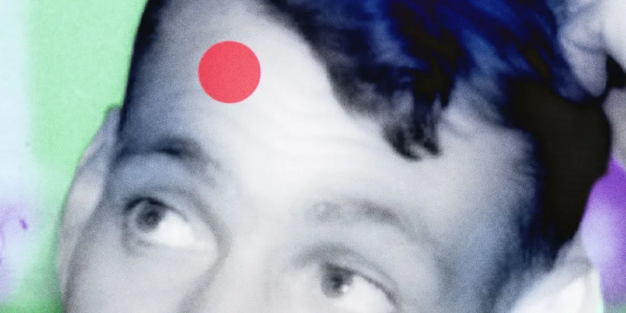 Primo piano di un volto con un punto rosso sulla fronte, come una crosta di brufolo schiacciato. Sfondo astratto verde e viola.
