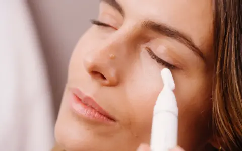 Donna applica siero contorno occhi con un applicatore. Scopri come applicare il siero contorno occhi per un look radioso.