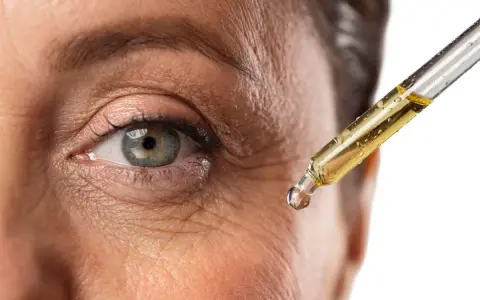 Goccia di siero con retinolo vicino all'occhio per combattere le rughe. Il retinolo cosa serve? A ringiovanire la pelle.