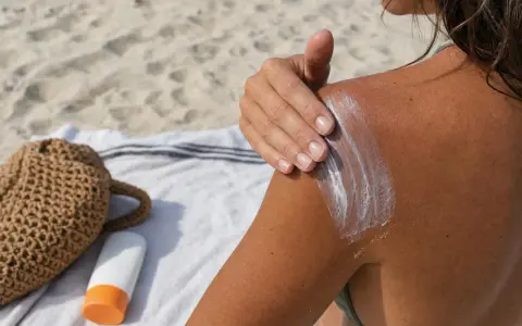 Protezione solare sulla spalla abbronzata, un gesto per prendersi cura della pelle e della melanina.