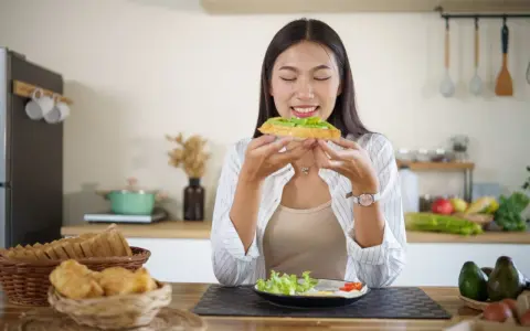Donna assapora un toast con avocado, un alimento ricco di vitamina E, essenziale per la pelle e il sistema immunitario.