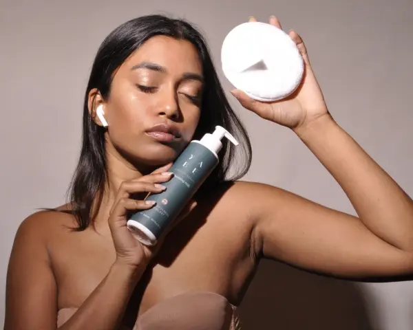 Donna con latte detergente e dischetto struccante, pronta per la pulizia del viso dopo il latte detergente il viso va lavato.