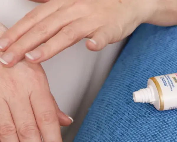 Mani che si toccano, alleviando rossore e prurito tra le dita. Accanto, un tubetto di crema Nivea.
