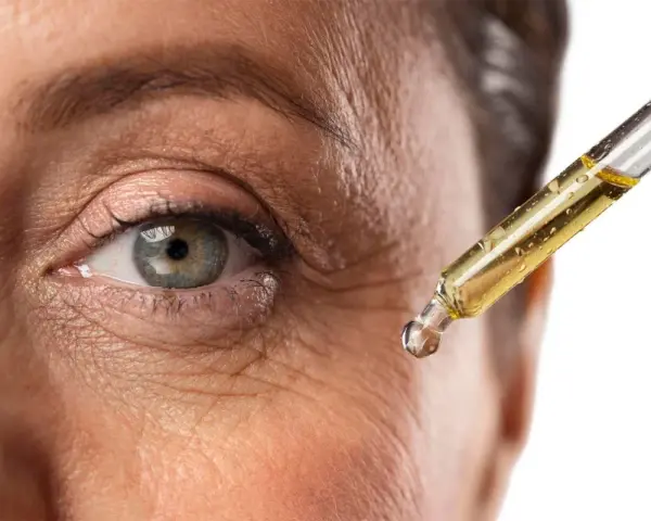 Goccia di siero con retinolo vicino all'occhio per combattere le rughe. Il retinolo cosa serve? A ringiovanire la pelle.