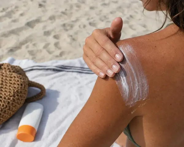 Protezione solare sulla spalla abbronzata, un gesto per prendersi cura della pelle e della melanina.