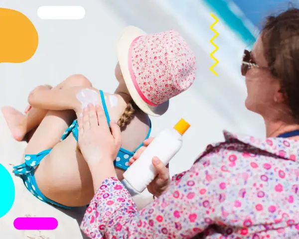Mamma applica la crema solare alla figlia sulla spiaggia. Ricorda, prendere il sole fa bene, ma con protezione!