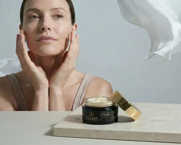 Donna con mani sul viso, vicino a un vasetto di crema. Soluzione per pelle secca viso rimedi.