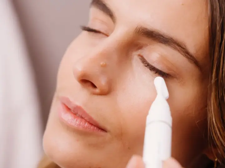 Donna applica siero contorno occhi con un applicatore. Scopri come applicare il siero contorno occhi per un look radioso.