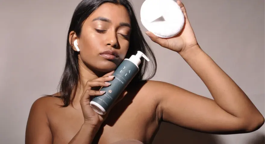 Donna con latte detergente e dischetto struccante, pronta per la pulizia del viso dopo il latte detergente il viso va lavato.