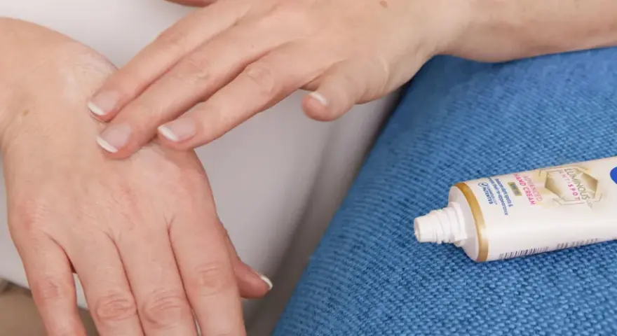 Mani che si toccano, alleviando rossore e prurito tra le dita. Accanto, un tubetto di crema Nivea.