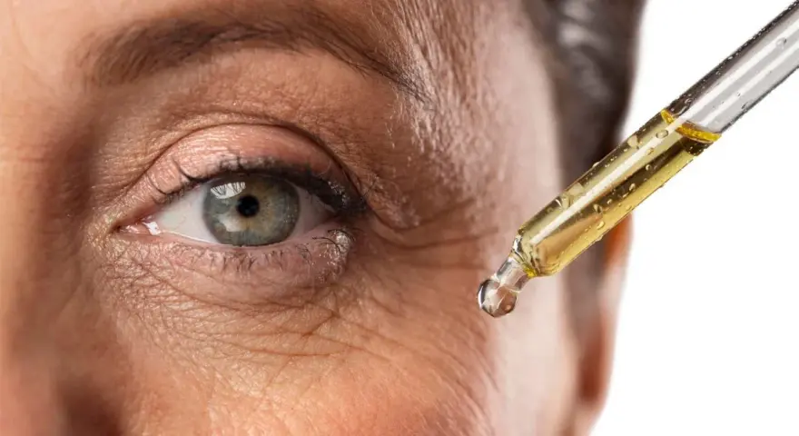 Goccia di siero con retinolo vicino all'occhio per combattere le rughe. Il retinolo cosa serve? A ringiovanire la pelle.