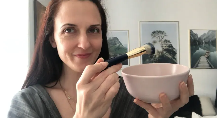 Donna prepara una maschera viso fai da te con bicarbonato, usando un pennello per applicarla.
