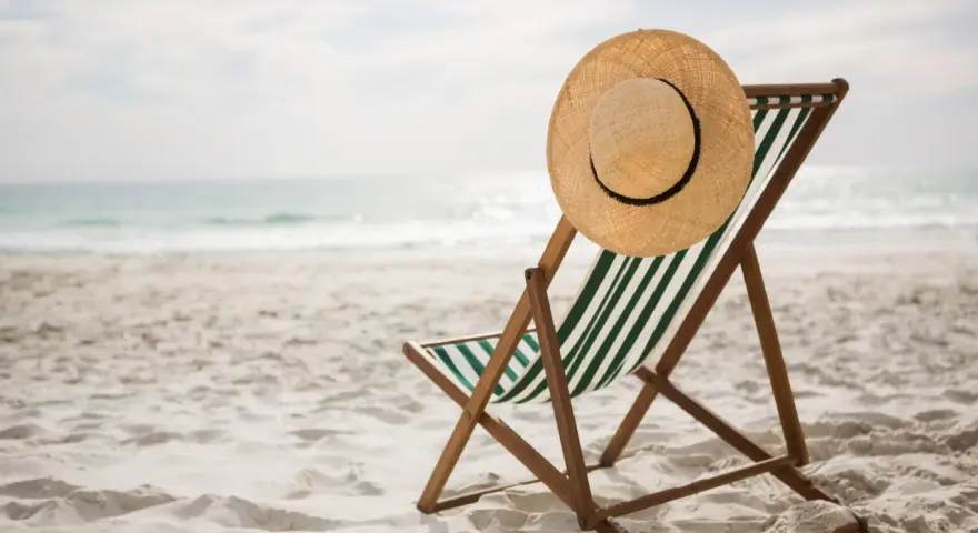 Spiaggia deserta con sdraio e cappello di paglia. Ricorda i rimedi per il colpo di calore: idratarsi e cercare l'ombra.
