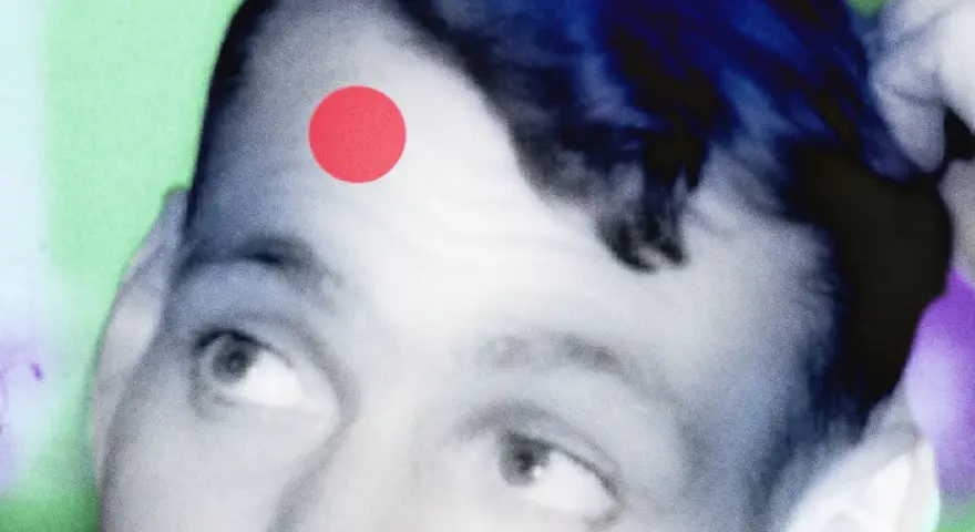 Primo piano di un volto con un punto rosso sulla fronte, come una crosta di brufolo schiacciato. Sfondo astratto verde e viola.