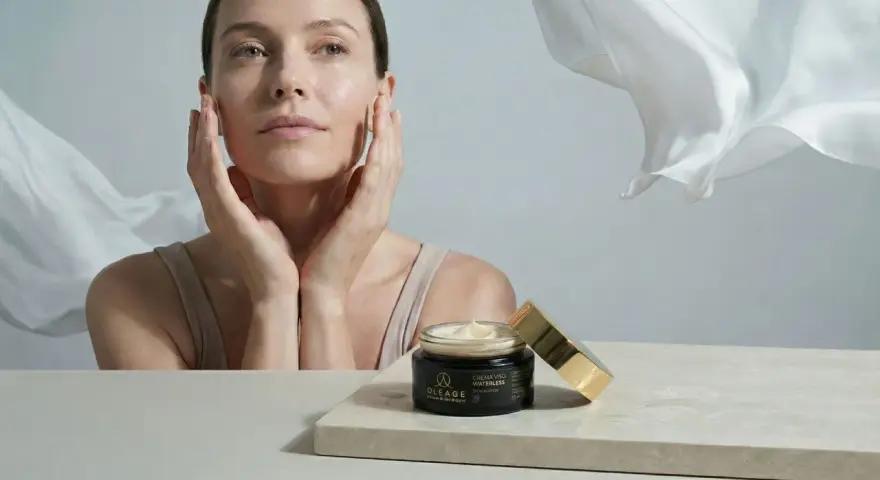 Donna con mani sul viso, vicino a un vasetto di crema. Soluzione per pelle secca viso rimedi.