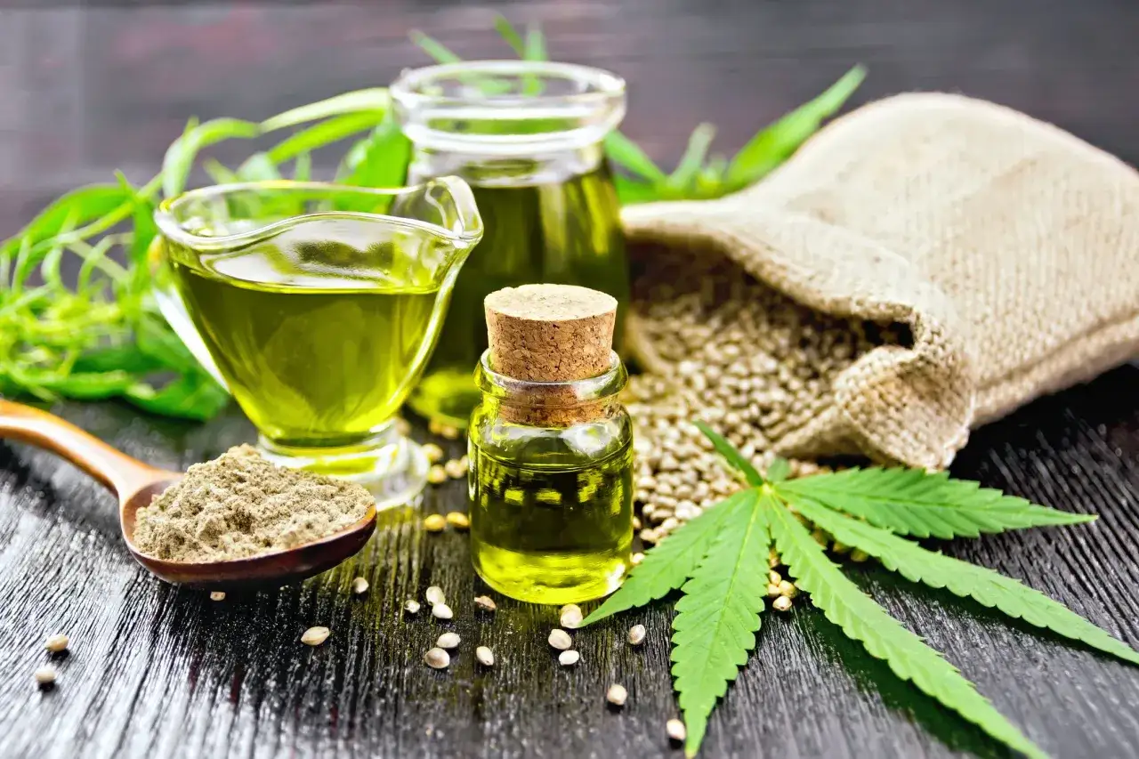 Olio di canapa a cosa serve? Scopri i benefici di questo olio verde brillante, estratto dai semi e dalle foglie di canapa, presentato in bottigliette e cucchiaio.