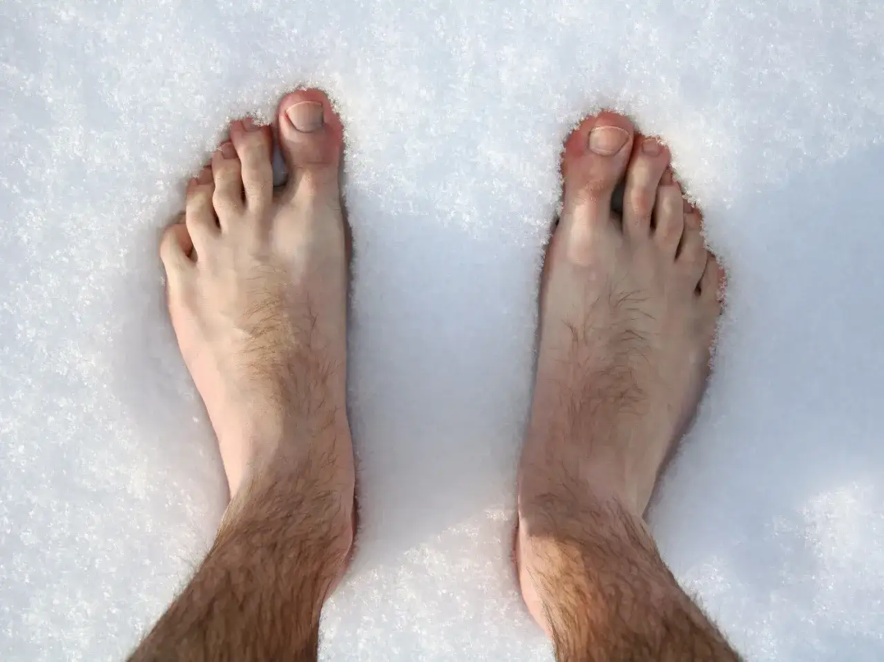 Piedi nudi nella neve, con le dita arrossate e la pelle che sembra soffrire di geloni.