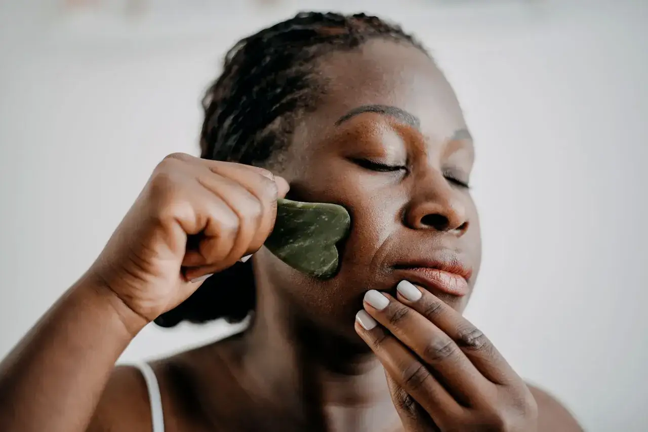 Donna usa un gua sha viso per un massaggio rilassante.