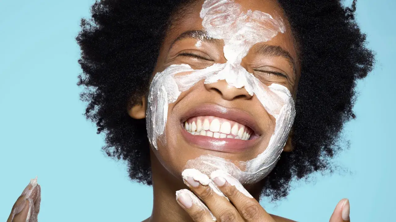 Donna con maschera viso bianca, sorride. Forse la crema solare tutti i giorni fa male?