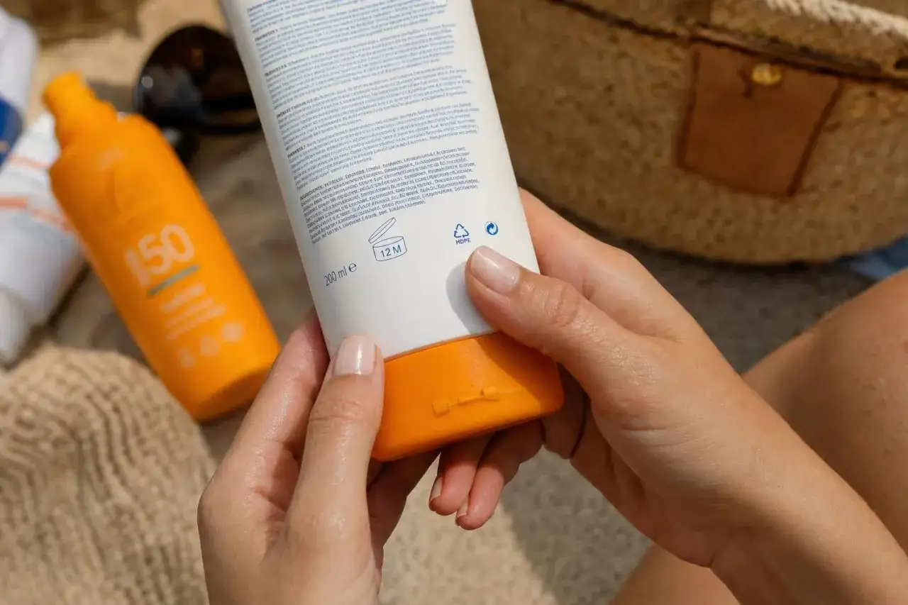 Mani che tengono una crema solare SPF 50. L'etichetta indica 12 mesi dopo l'apertura, suggerendo la scadenza crema solare non aperta.