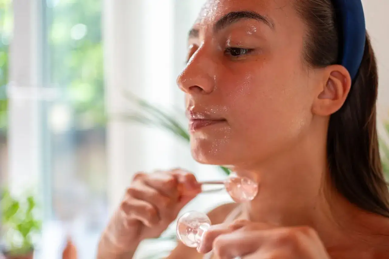 Donna usa sfere di ghiaccio sul viso, un rimedio naturale per i brufoli. La pelle &egrave; luminosa e idratata.